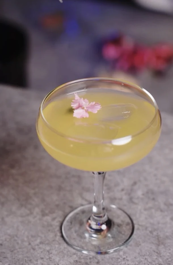 Cocktail jaune décoré d’une fleur rose